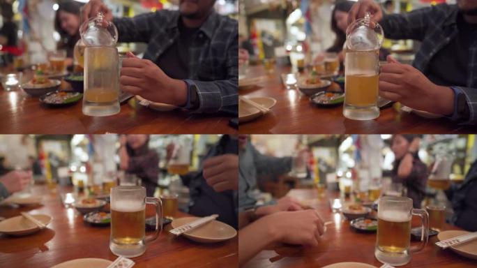 亚洲男子在日本餐厅为同事倒啤酒