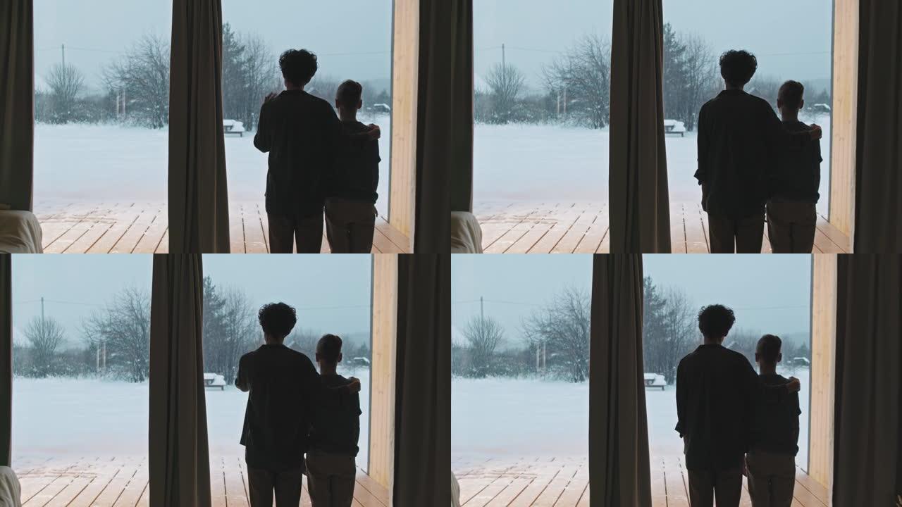 妈妈和儿子在冬天站在全景窗户旁