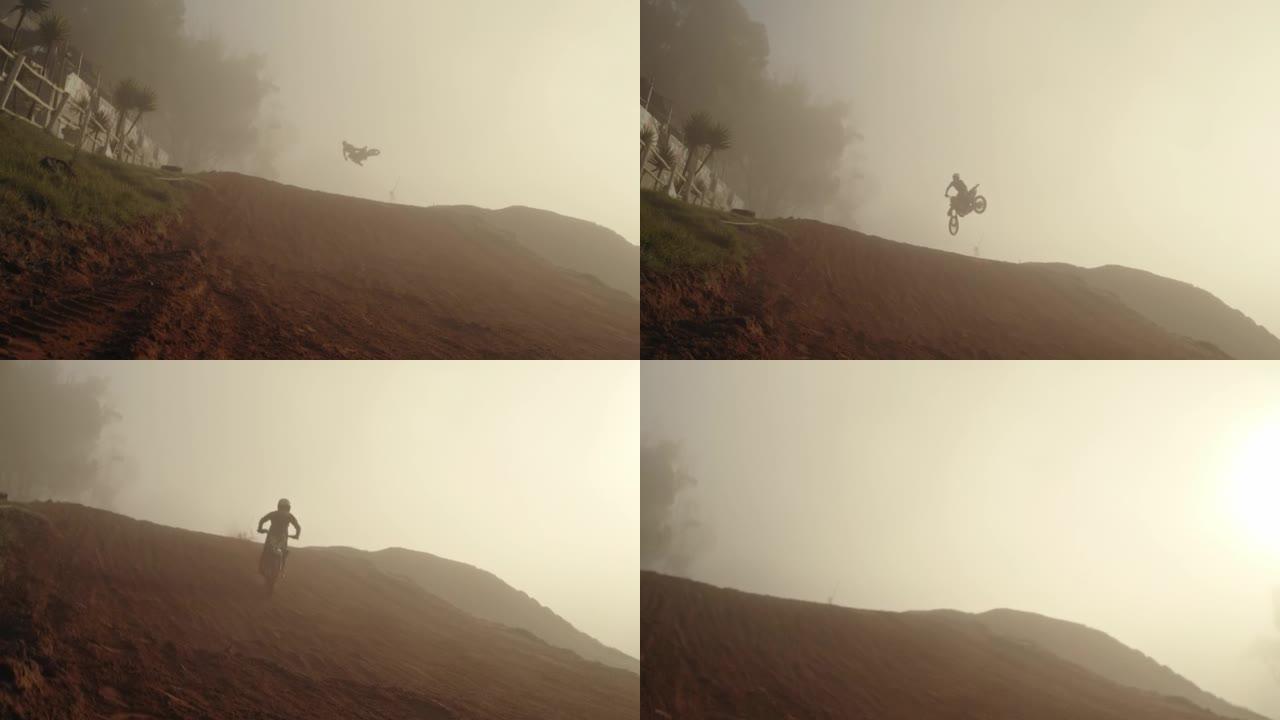 运动摩托车、摩托车越野人或自行车训练，并在晨雾中在灰尘、沙子和土路山上跳跃。手持慢动作运动员，具有健