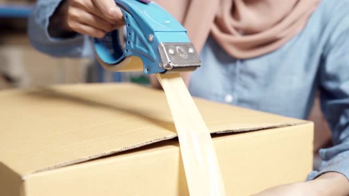 4K UHD特写多莉左: 伊斯兰穆斯林女性亚洲仓库工人在仓库配送中心包装包裹。在企业仓库物流概念中的