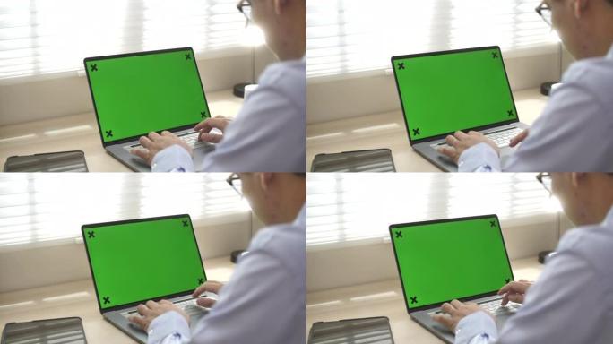 男人使用带有绿色屏幕的笔记本电脑