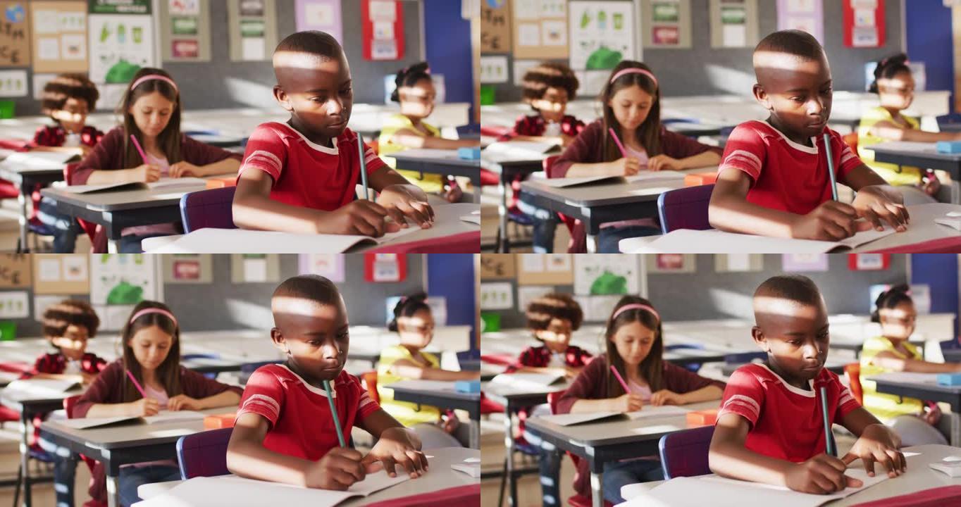 非裔美国男生的肖像坐在课堂上，做笔记，看着相机