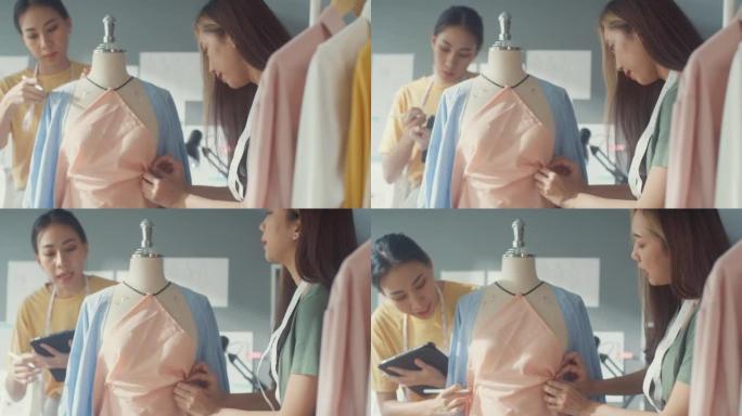 两位专业的亚洲开朗的女士时装设计师团队合作，用假人上的数字平板测量卷尺在商店里创造服装设计。女士裁缝