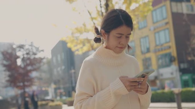 亚洲妇女在公园散步时正在用手机做生意。