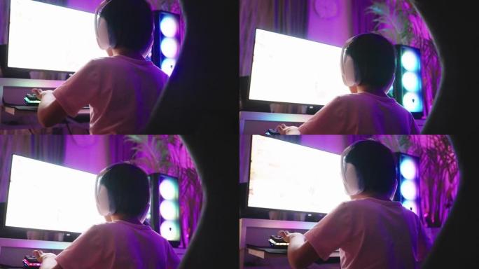 小男孩streamer正在家里的PC电脑上玩电子游戏。