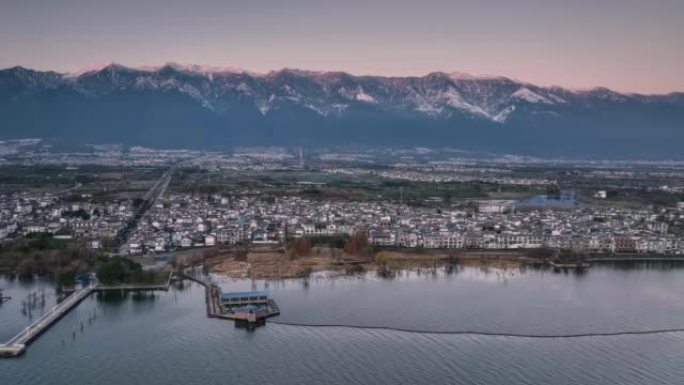 绵延的雪山下，有大片民居和一个大湖