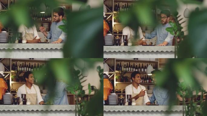 4k视频片段，一个英俊的年轻人与他的服务员站在咖啡馆里并使用数字平板电脑