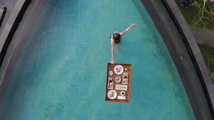 鸟瞰图女人在游泳池吃早餐，在豪华酒店水疗中心享受异国美食，可以看到热带丛林