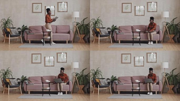 黑人妇女坐在沙发上并通过视频通话在线学习