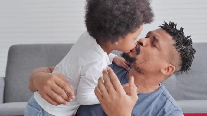 非洲父亲和小男孩的家庭一起花时间在家里接吻。爸爸和孩子温柔的时刻。父亲，父亲节，庆祝，团结，联系，钦
