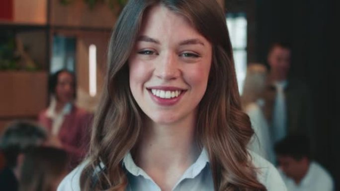 面对美丽的年轻快乐的女经理，自由企业家在镜头前摆姿势，在现代办公室微笑。