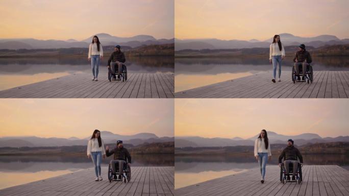 妇女与残疾丈夫坐在轮椅上在码头上行走