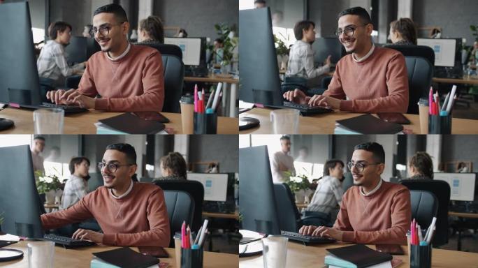 快乐的阿拉伯男人在办公室里用电脑打字看屏幕的慢动作