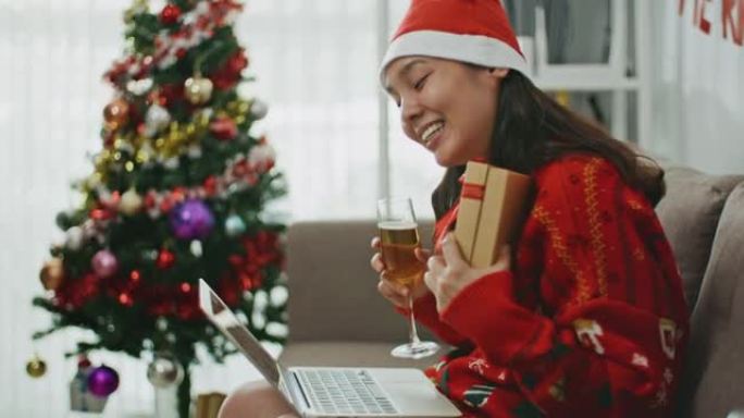 亚洲妇女使用笔记本电脑通过视频通话祝贺朋友或家人圣诞快乐