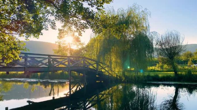 日落时分在河上的木桥上郁郁葱葱的树叶风景