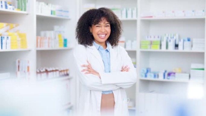 自信的非洲裔美国化学家站在她的药架前。白大褂专家交叉双臂欢笑。药剂师对她的营业额感到满意