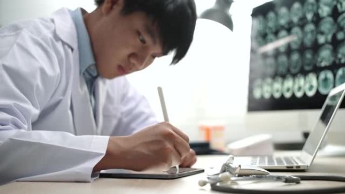 亚洲男医生在医院办公室的办公桌上使用数字平板电脑