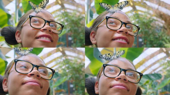 脸、蝴蝶和孩子头上戴着昆虫的女孩戴着眼镜从下面特写。春天，自然和孩子在公园或自然环境中站着戴眼镜的女