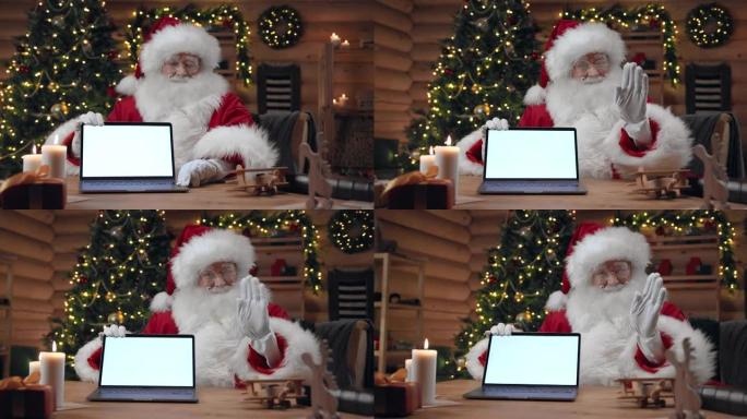 圣诞老人打开一台空屏幕的笔记本电脑，在相机中挥手