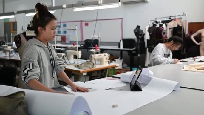 亚洲中国女性时尚大学生剪纸形状缝纫图案在大学工作坊做服装项目