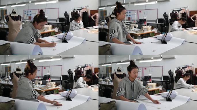 亚洲中国女性时尚大学生剪纸形状缝纫图案在大学工作坊做服装项目