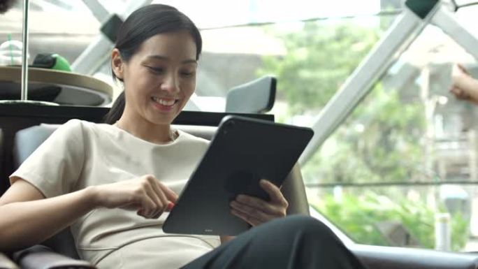 使用数字平板电脑在咖啡馆工作的亚洲女性