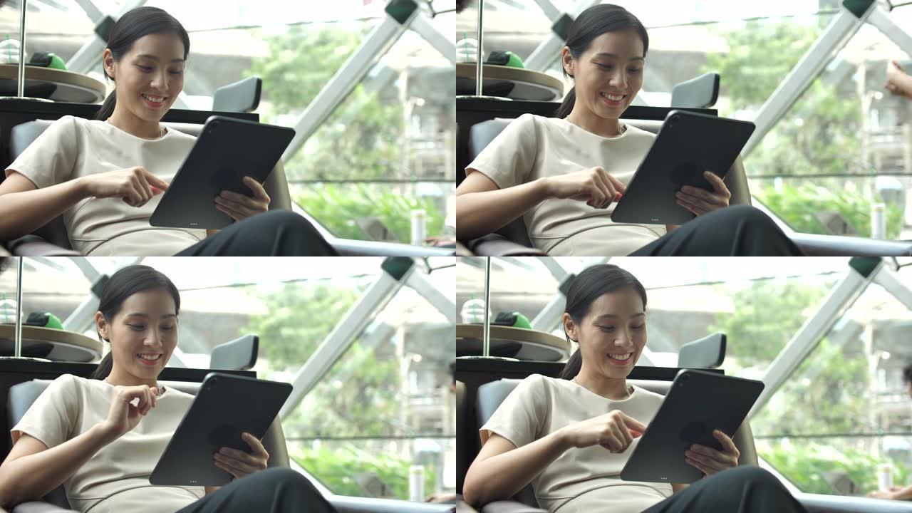 使用数字平板电脑在咖啡馆工作的亚洲女性
