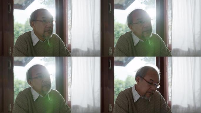 特写: 悲伤的老退休白发爷爷亚洲男子独自坐在窗前的桌子旁无聊地呆在家里自我隔离检疫在问题精神卫生中感