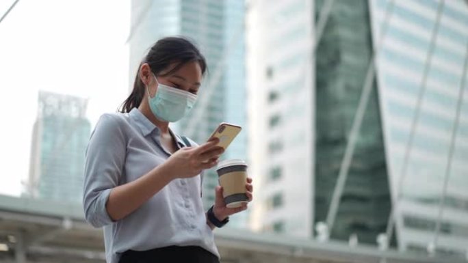 亚洲女商人在城市使用带口罩的手机