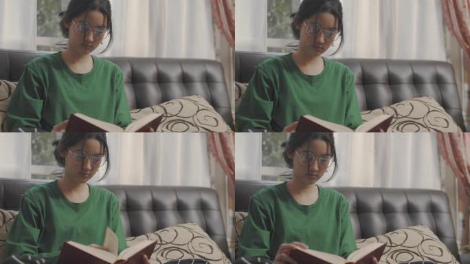 手持视点镜头: 亚洲少女呆在家里读一本模拟书。她翻开学习书的一页。亚洲学生在她家的学校学习历史课作业