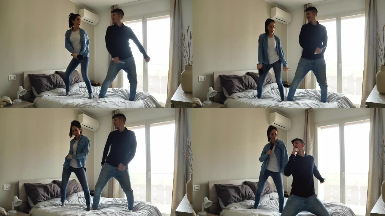 一对年轻的无忧无虑的恋爱夫妇的真实照片是在卧室的床上唱歌和跳舞的乐趣。