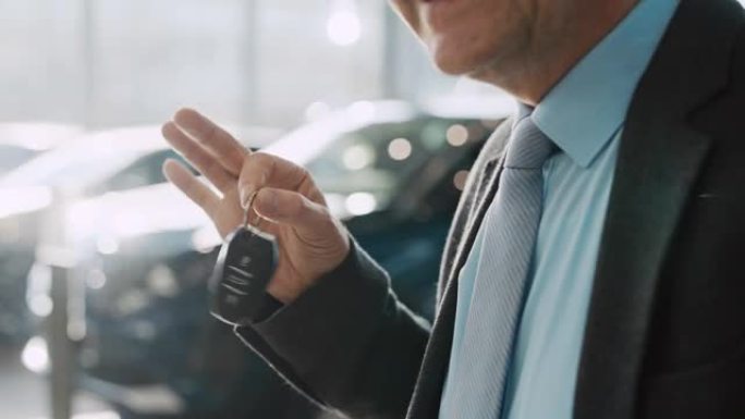 SLO MO汽车推销员在汽车陈列室里用汽车钥匙挥手