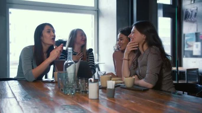 一群快乐成功的年轻女性朋友一起聊天和欢笑，在咖啡店会议上分享亲密的时间。