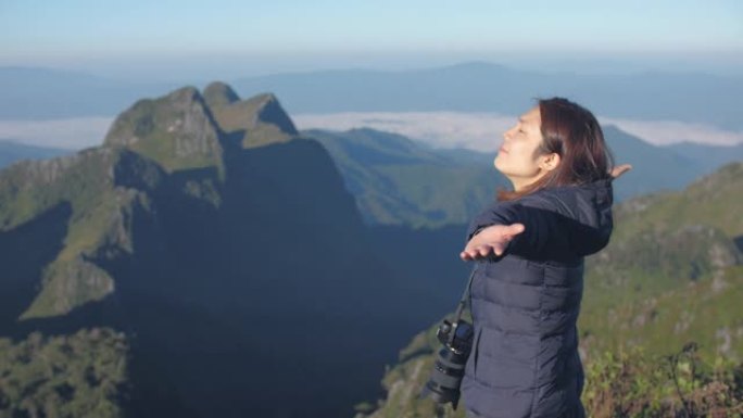 女人爬到山顶，举手庆祝成功