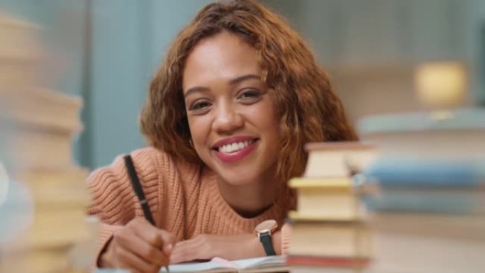 一个年轻的黑人妇女在家里的桌子上做作业的肖像。一个微笑的非洲裔美国女性，卷发，成堆的书学习和写笔记。