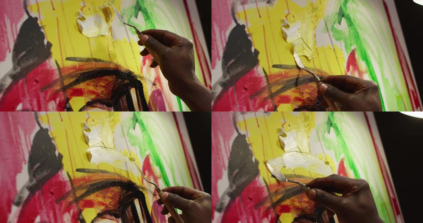 在艺术工作室用调色板刀在画布上绘画的男性艺术家的手的特写