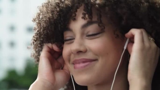 4k视频片段，一个美丽的年轻女子戴着耳机站在城市外面