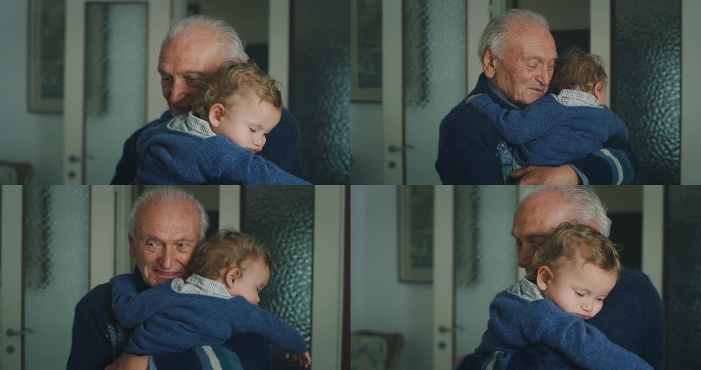 一个快乐的祖父的电影镜头是抱着他睡着的孙子宝宝的爱，享受在家一起打发时间。生活观念，祖父母，世代，童