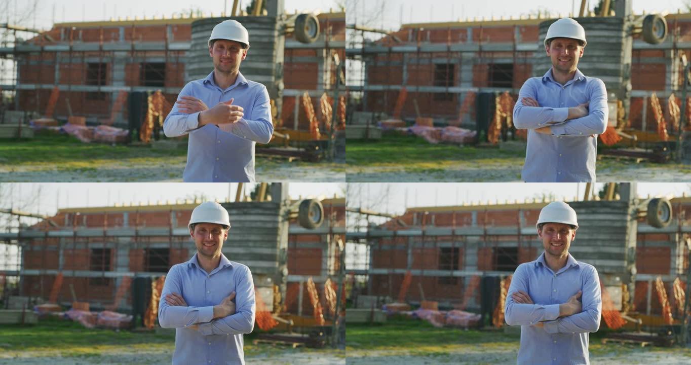 一位年轻的工程师在镜头前微笑着，对他在建筑工地背景下的工作感到满意。概念: 服务、建筑、事业人、建筑