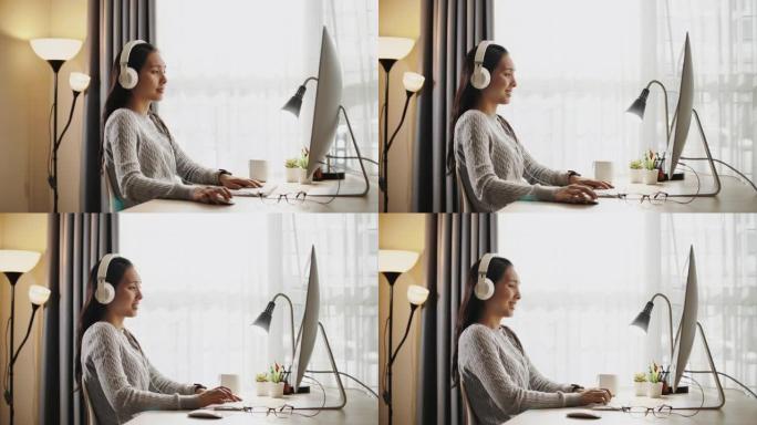 亚洲妇女在家里使用电脑时戴着耳机听音乐