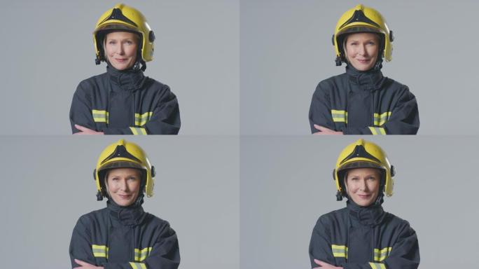 工作室肖像微笑成熟的女消防员戴着头盔在朴素的背景下