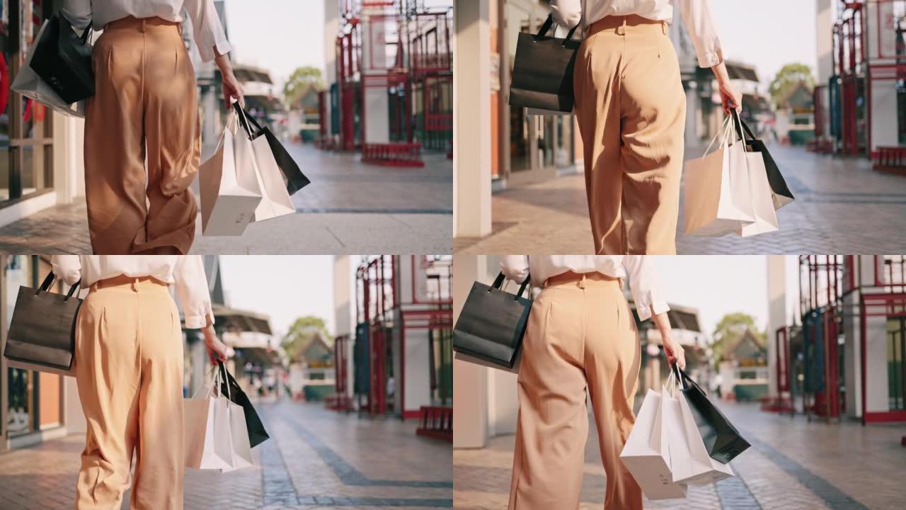 年轻女子的腿和购物纸袋的后视图