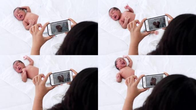 母亲在床上为他的新生儿拍照