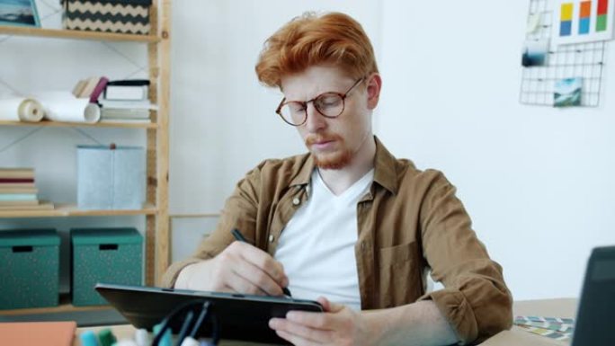 年轻男子设计师的肖像在家室内使用平板电脑绘图