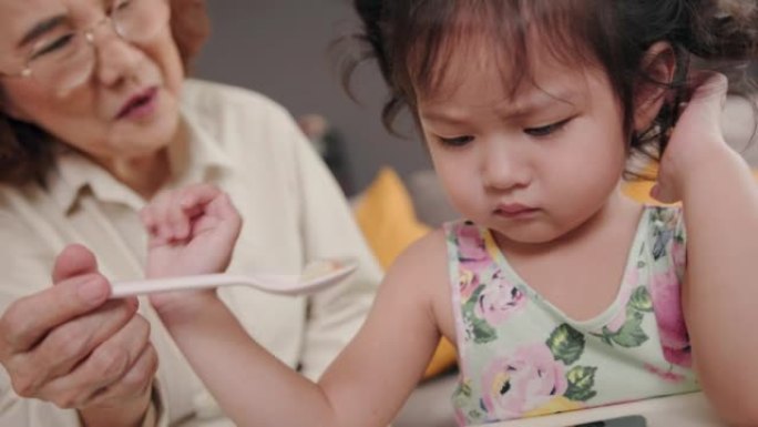 孩子对不得不吃食物非常不满。孙女在数字平板电脑上玩。