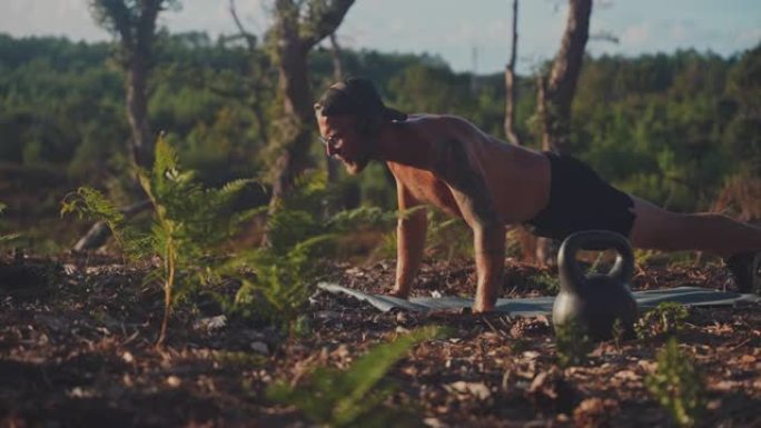 年轻的运动员在树林里的运动垫上做俯卧撑