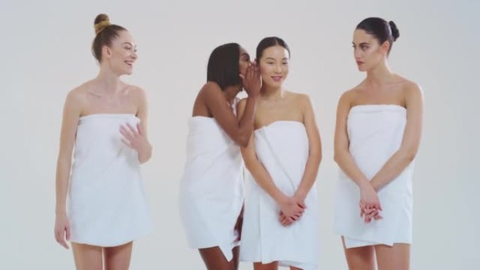 慢动作美丽的年轻女性的不同种族与完美的公司和苗条的身体在白色浴巾看和微笑在相机孤立的白色背景。