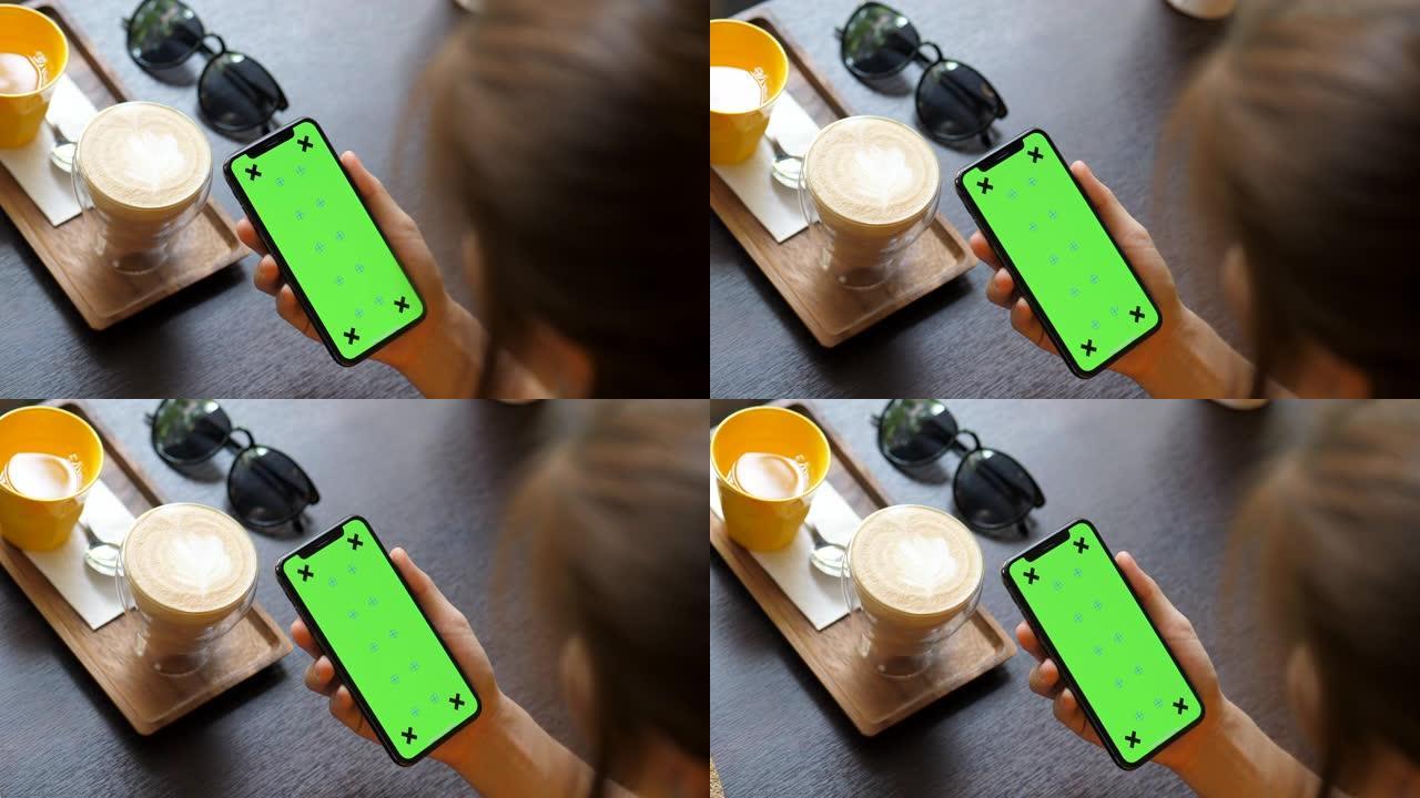 咖啡馆里拿着绿屏智能手机