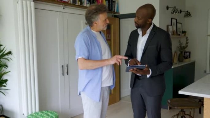 一名男子与他的房地产经纪人谈论买房，并在平板电脑上查看抵押贷款条件