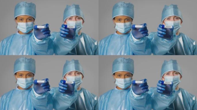 工作室拍摄的照片中，女性实验室研究人员穿着个人防护用品，手持标有Covid-19和欧米克隆的试管